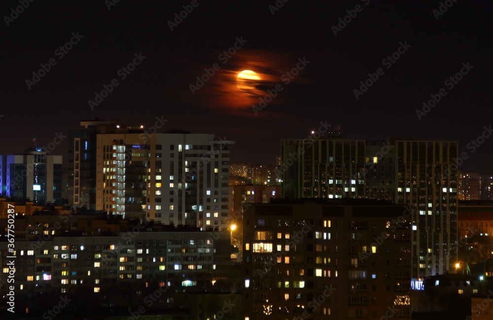 
Full moon in the clouds in the city. High-rise buildings from above in the foreground