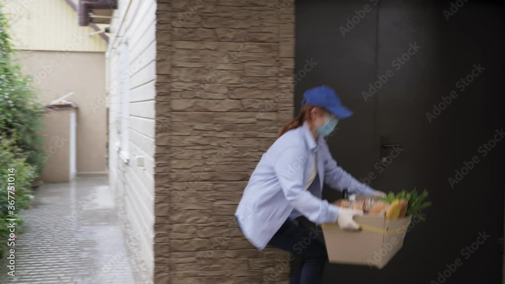 groceries home, female courier wearing medical mask and gloves delivers basket of groceries to girl sitting at home isolated during a pandemic due to virus and infection groceries home, female courier wearing medical mask and gloves delivers basket of groceries to girl sitting at home isolated during a pandemic due to virus and infection