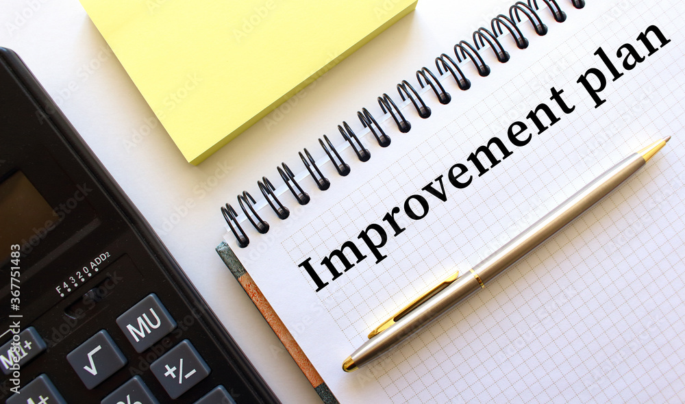 Notepad with text IMPROVEMENT PLAN, next to it lies a calculator and yellow note papers. Business concept. Notepad with text IMPROVEMENT PLAN, next to it lies a calculator and yellow note papers. Business concept.