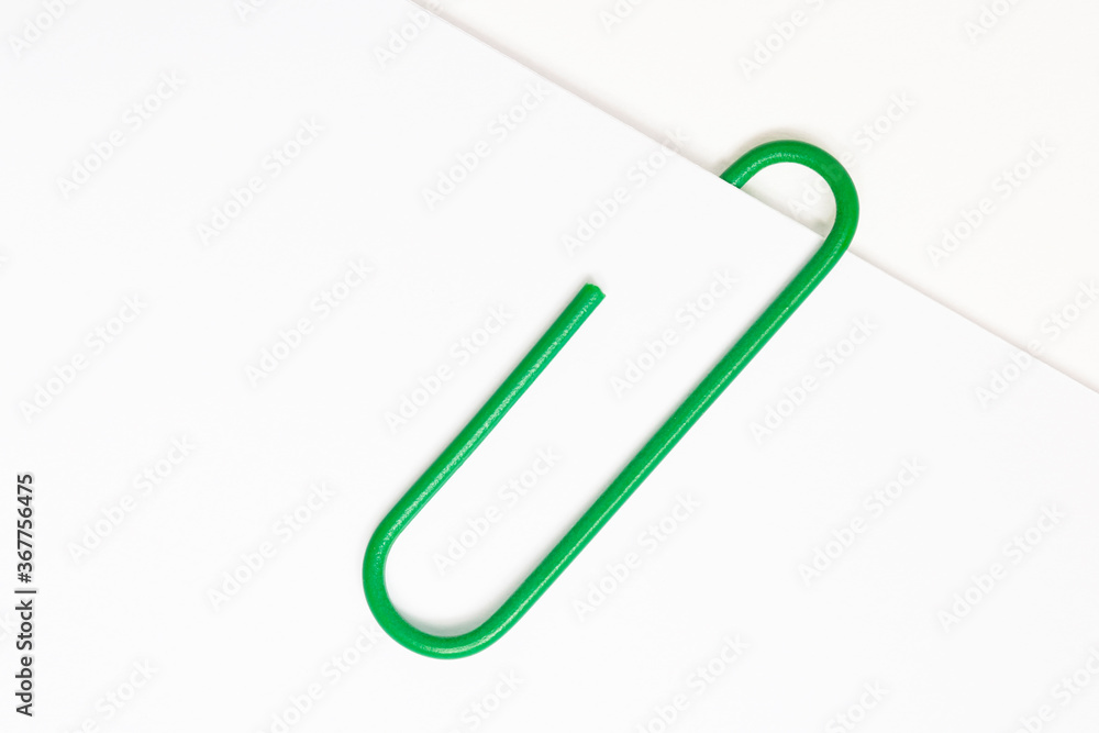 Obraz premium Green paper clip on white paper 
