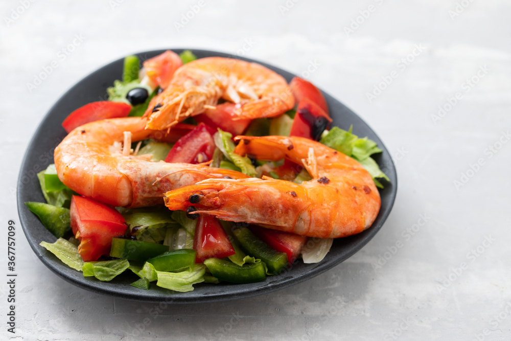 salad with fried shrimps on dark plate on ceramic background salad with fried shrimps on dark plate on ceramic background