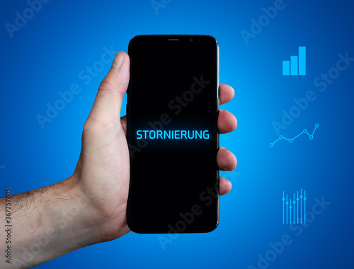 Stornierung. Hand hält Telefon (Handy). Wort auf Display. Diagramme auf Hintergrund blau. Business photo