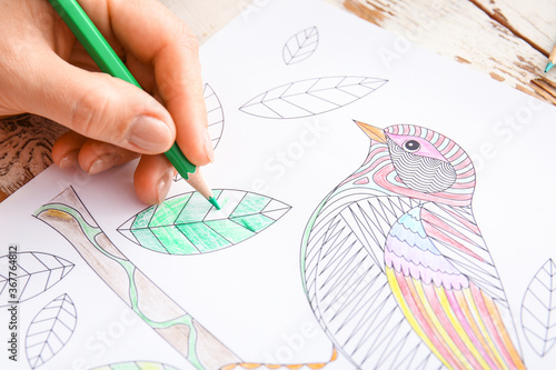 Woman coloring picture at table, closeup photo