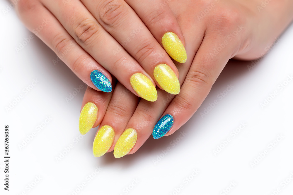 Yellow-blue manicure on sharp long nails on a white background close-up. Patriotic manicure. Ukraine. Yellow-blue manicure on sharp long nails on a white background close-up. Patriotic manicure. Ukraine.