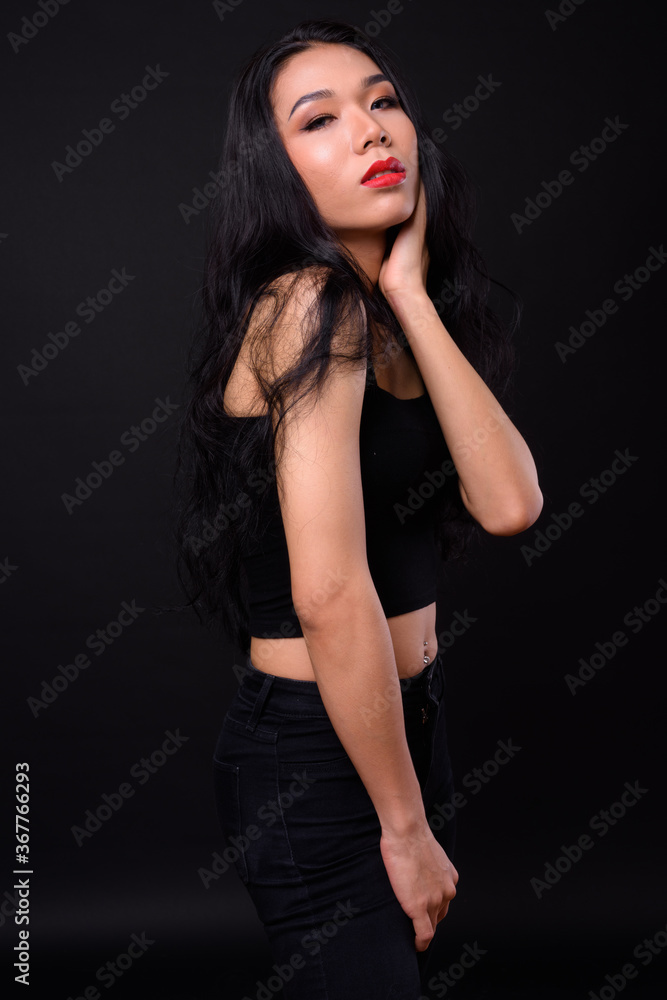 Young beautiful Asian transgender woman against black background