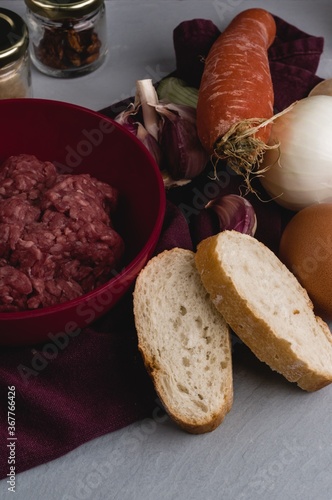 Verticcal closeup shot of ingredients for preparing meatballs on a white kitchen table photo