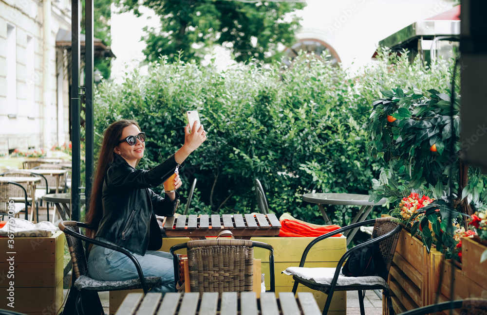 Young woman sitting and taking selfie in outdoor restaurant