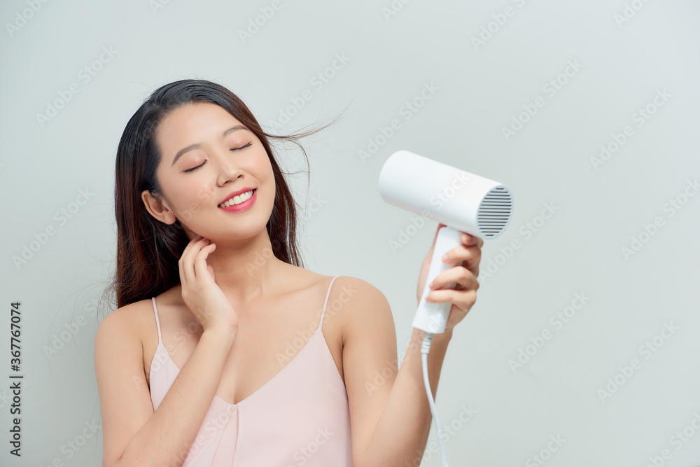 Young female drying her beautiful hair with hairdryer Young female drying her beautiful hair with hairdryer