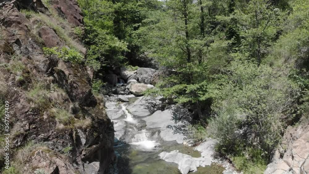 Drone flying over a river surrounded by a green forest in Europe Drone flying over a river surrounded by a green forest in Europe