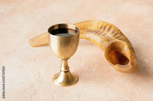 Shofar and sacramental goblet with wine on color background. Rosh Hashanah (Jewish New Year) celebration