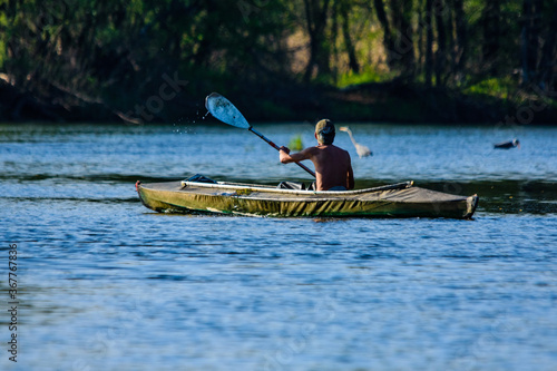 Young man kayaking on a river at summer