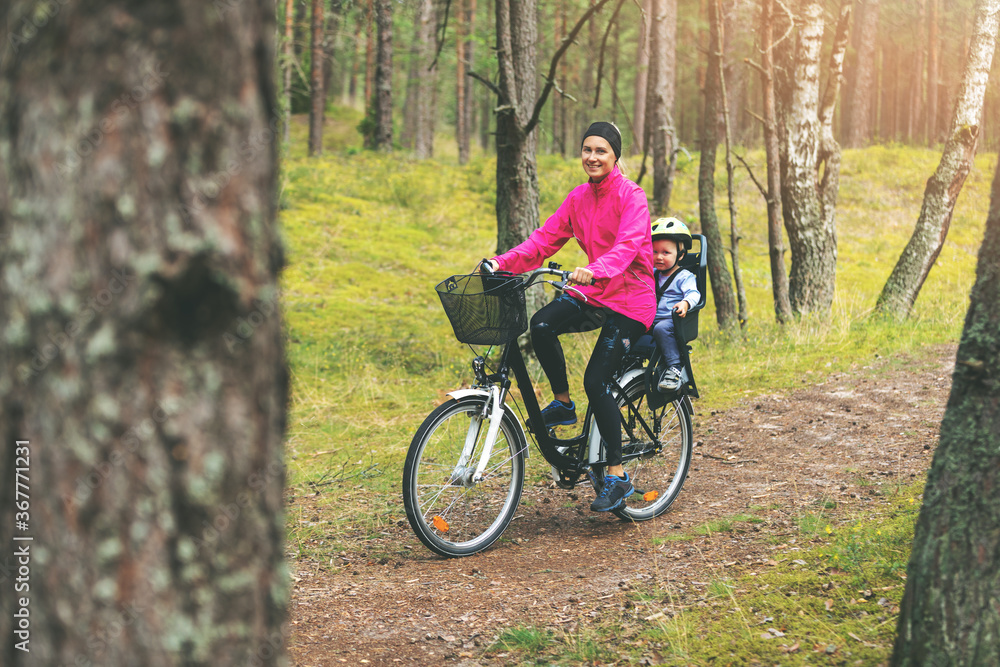 mother with son in bike child seat cycling on forest trail