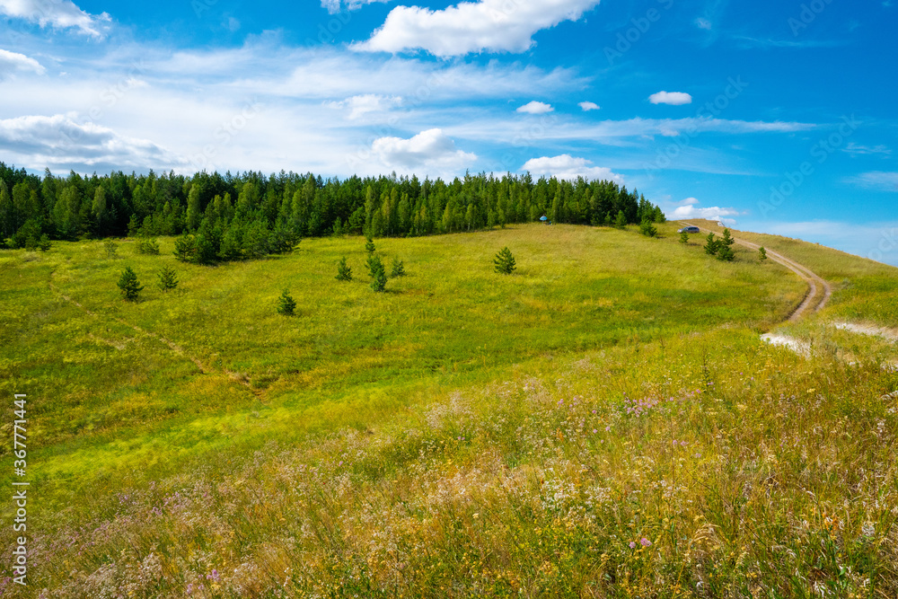 Panorama a picturesque landscape with hills and green lawns and a blue sky with clouds Panorama a picturesque landscape with hills and green lawns and a blue sky with clouds