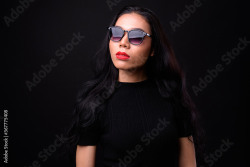 Young beautiful Asian transgender businesswoman against black background