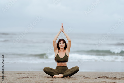 woman doing yoga exercises on the beach summer time