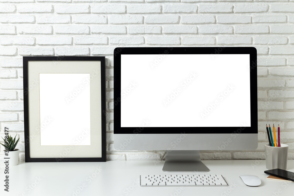 Fototapeta premium mockup computer with blank white screen and empty Poster frame with workspace and office supplies on desk