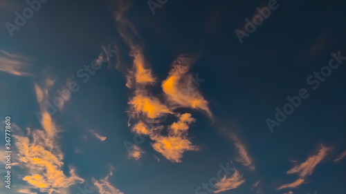 Small saffron clouds in blue sky at evening time