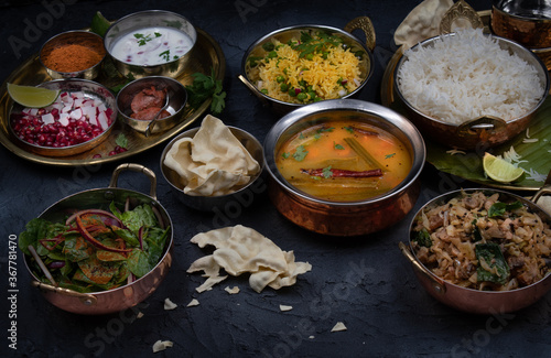 South Indian vegetarian food served on traditional platters and trays, black background