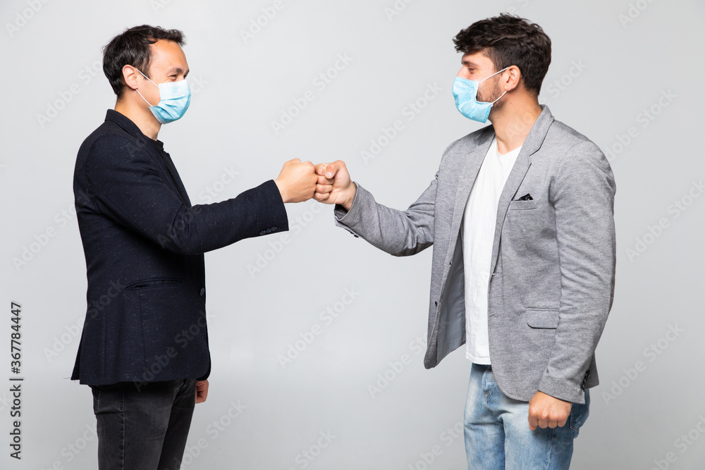 Fist bump greeting. Two people in suits greet each other in a meeting. They give up the untraditional handshake isolated on a white background. Covid concept Fist bump greeting. Two people in suits greet each other in a meeting. They give up the untraditional handshake isolated on a white background. Covid concept