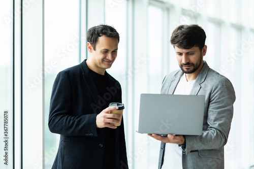 Business two men at informal meeting looking at laptop in the office building