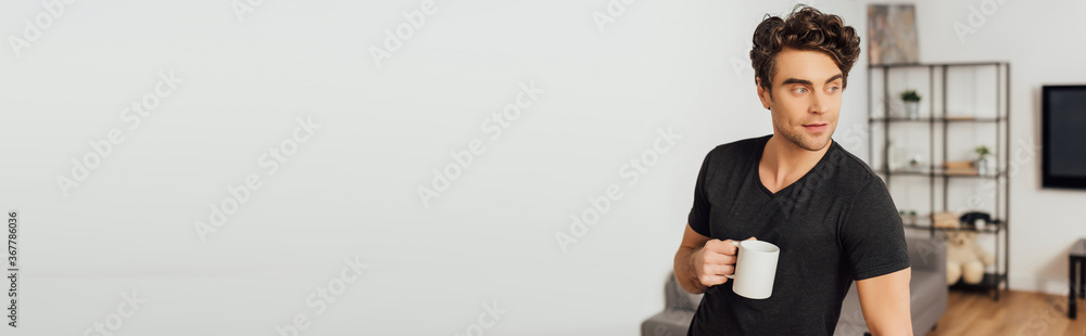Panoramic shot of handsome man holding cup of coffee at home Panoramic shot of handsome man holding cup of coffee at home