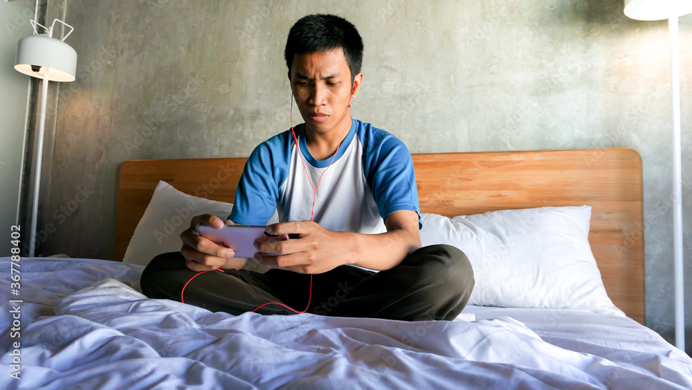 Asian man is playing games in the bedroom Asian man is playing games in the bedroom