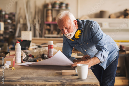 Close up of a carpenter thoughtfully reading blueprints