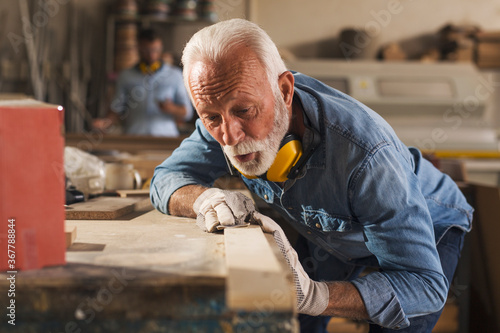 Portrait of an professional elderly carpenter using sandpaper