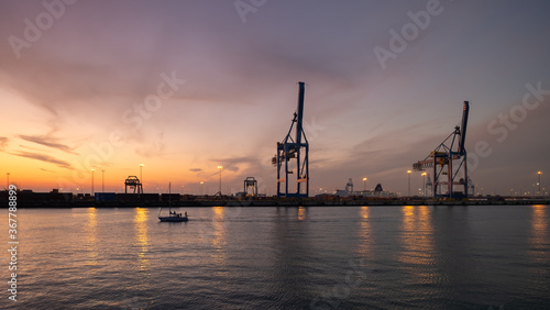 Container terminal in the port of Zeebrugge at sunset. View from the viewing platform near the monument "Visserskruis"