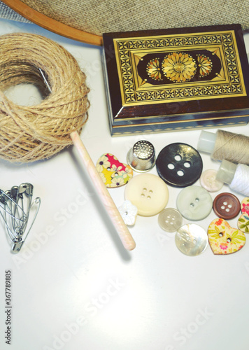Sewing accessories in beige and ecru colours including vintage wooden box, sewing spools, buttons, jute cord. Scrapbooking and DIY. Hobby and needle work background. Retro style. 
