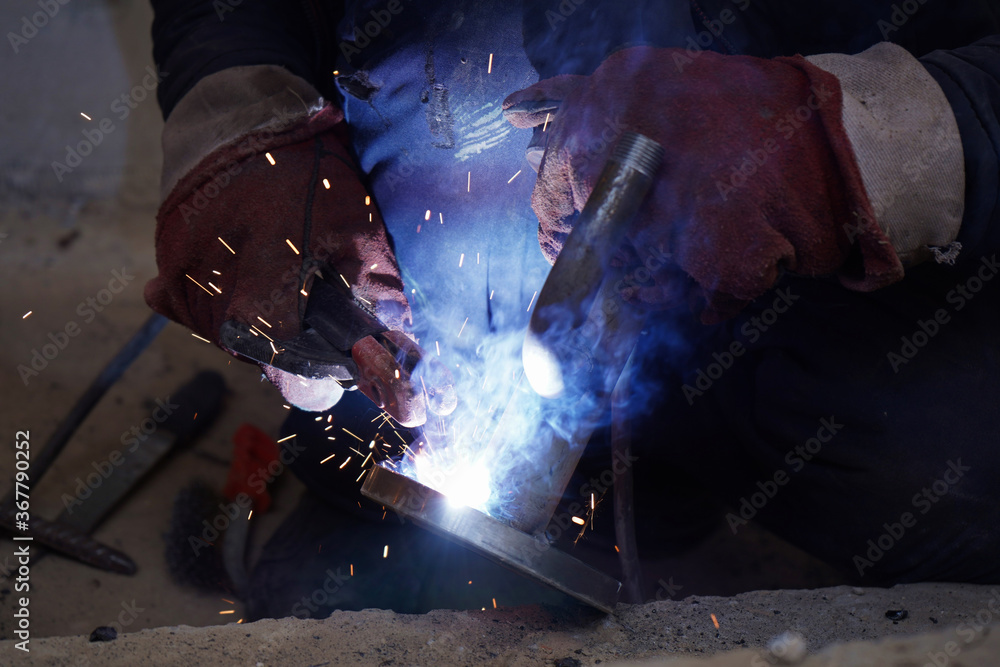 Close-up welder working with electrode at semi-automatic arc welding in manufacture production plant.Bright sparks from welding. Close-up welder working with electrode at semi-automatic arc welding in manufacture production plant.Bright sparks from welding.