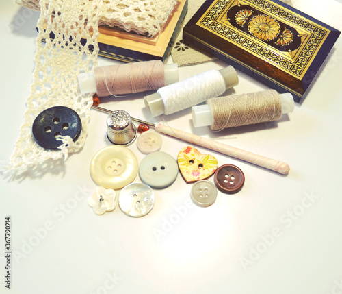Closeup of working place of tailor or fashion designer with cotton lace, vintage wooden box, sewing spools, buttons, crochet, linen fabrics. DIY, hobby, embroidery, needlework. Retro style 

