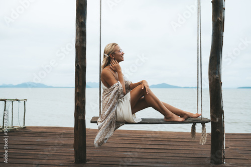 Woman in dress boho style sitting at seaside in cafe in old town koh Lanta, Thailand