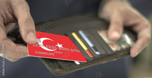 Fototapeta Naklejka Na Ścianę i Meble -  Man pulls plastic card with flag of Turkey out of his wallet, fictional card number