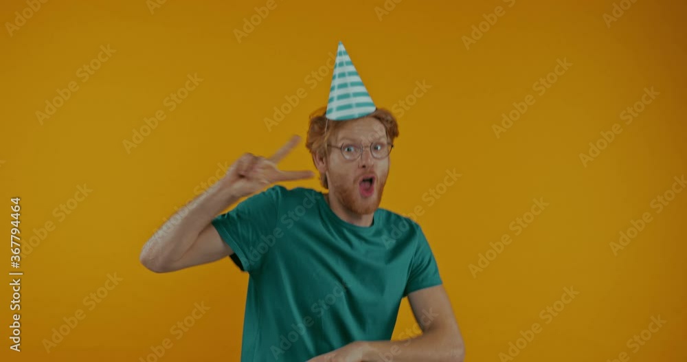 happy redhead man in party cap dancing isolated on yellow happy redhead man in party cap dancing isolated on yellow
