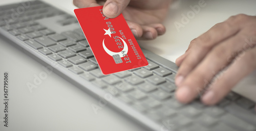 Fototapeta Naklejka Na Ścianę i Meble -  Man pays online with plastic bank card with printed flag of Turkey. Fictional numbers