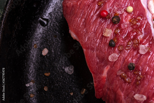 Fresh Beef for Steak New York Sprinkled Served with Mix Pappercorns, Large Crystals of Himalayan Pink Salt, Smoked Brown Salt Crystals Lies in a Cast-Iron Vintage Pan. View From Above. CloseUp. photo