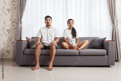 Schilderij op canvas Sad bored couple sitting on sofa at home