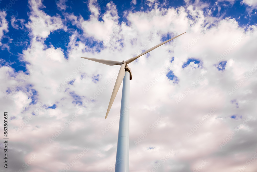 Tall, modern wind turbines spinning to generate renewable electricity with a cloud sky in the background. Tall, modern wind turbines spinning to generate renewable electricity with a cloud sky in the background.