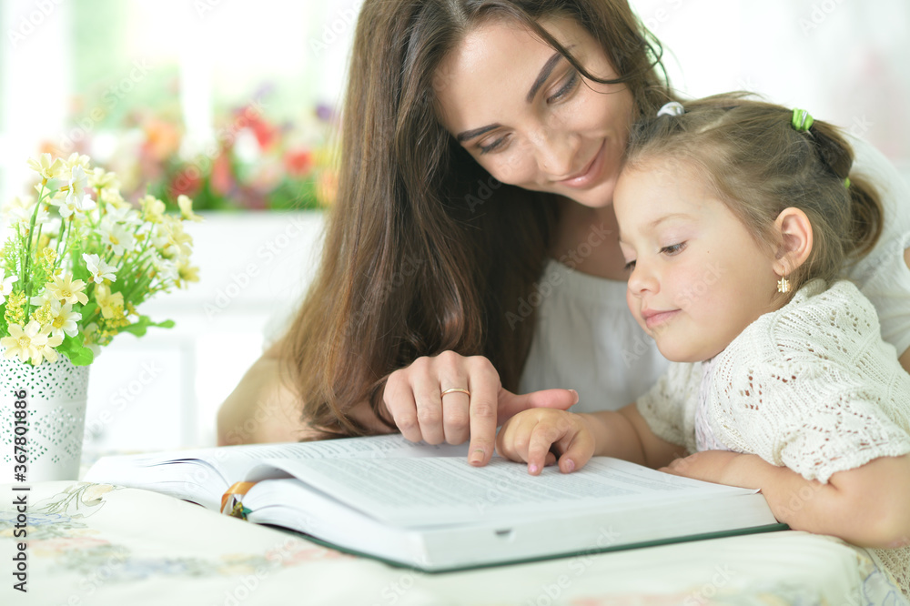 Portrait of little cute girl with mother reading book at home Portrait of little cute girl with mother reading book at home