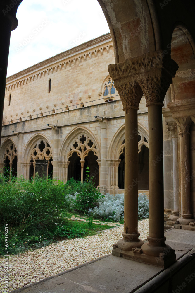 Courtyard from under the arches of the vaulted galleries of the monastery of Poblet (cat. Reial Monestir de Santa Maria de Poblet) Spain.