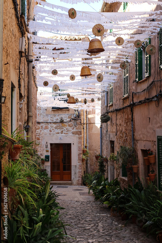 sun protection and wicker products suspended between houses on a narrow street in the city of Valdemossa. Majorca. Spain.
