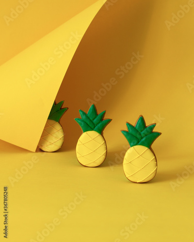 Gingerbread pineapples on a yellow background with copy space. Modern style on colored paper. Bright juicy colors