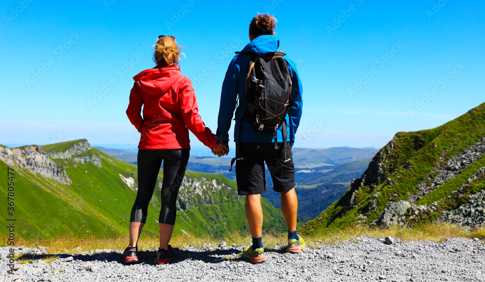hikers couple with backpack standing on the top of mountain, enjoying mountain panorama