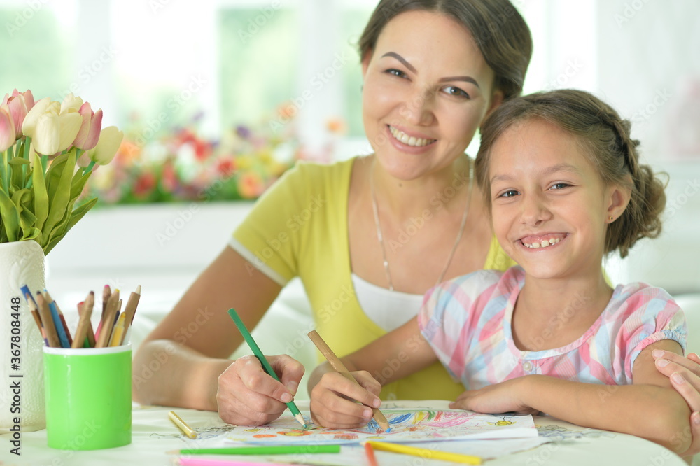 Cute girl with mother drawing at the table at home Cute girl with mother drawing at the table at home