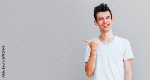 Fotografia Cheerful toothy stylish man pointing with finger.