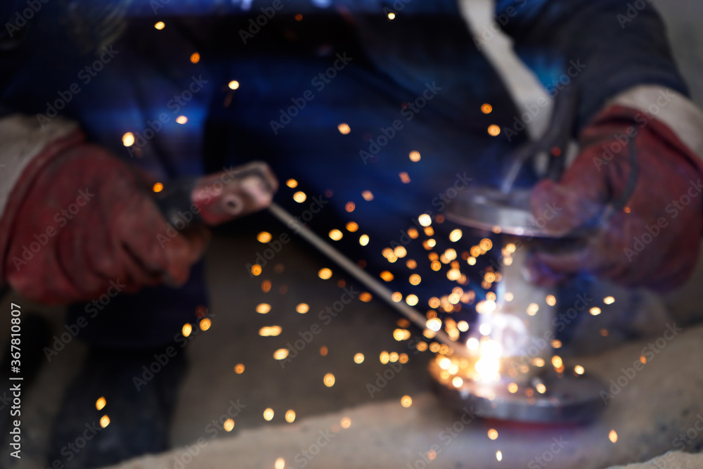 Obraz premium No focus.Close-up welder working with electrode at semi-automatic arc welding in manufacture production plant.Bright sparks from welding.