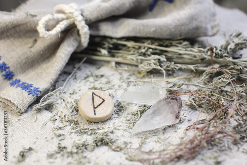 Scandinavian wooden rune Wunjo, Wynu, winja on a rough linen cloth with amethyst crystalline, rock crystal and dried wormwood