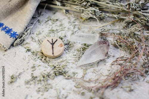 Scandinavian wooden rune Algiz, Elhaz on a rough linen cloth with amethyst crystalline, rock crystal and dried wormwood