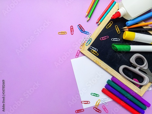 Chalkboard, colored pencils on a purple background. Back to school.